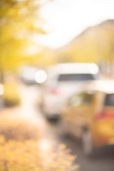 Autumn season bokeh background. Abstract city blur along the road with cars