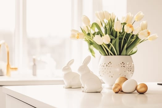 Easter table setting with tulips, Easter bunnies, and eggs with golden patterns in the white Scandinavian-style kitchen background. Beautiful minimalist design for greeting card.