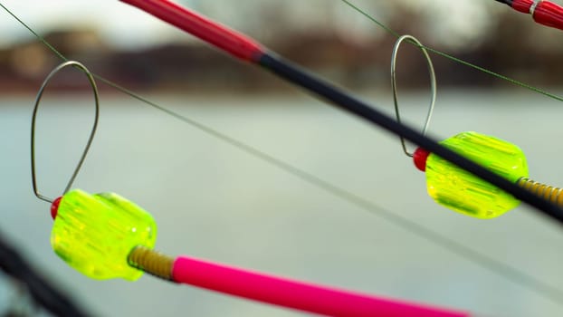 The bite alarm hangs on a fishing rod against the background of water. Fishing rod while fishing on the lake, river. Fishing tackle. Carp rod on a stand with a bite alarm on the line