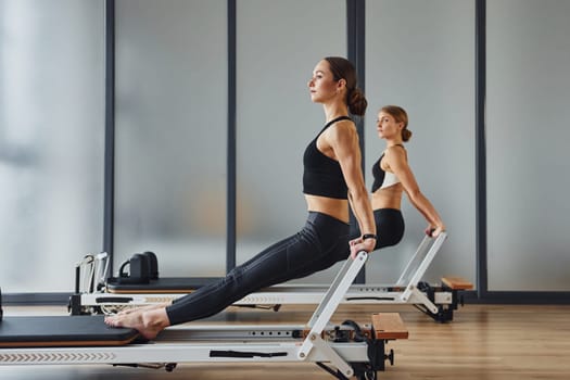 Hands strength. Two women in sportive wear and with slim bodies have fitness yoga day indoors together.