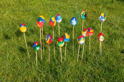Painted colorful Easter eggs on wooden skewers in green grass