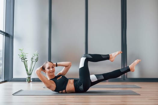 Concentrated on exercise. Young woman in sportive wear and with slim body have fitness yoga day indoors.