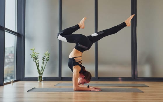 Concentrated on exercise. Young woman in sportive wear and with slim body have fitness yoga day indoors.