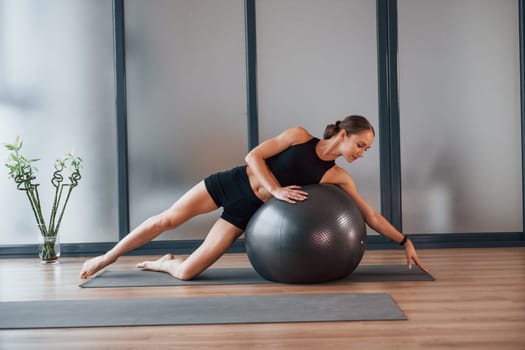 Taking a break. Young woman in sportive wear and with slim body have fitness yoga day indoors.