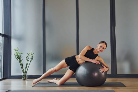 Taking a break. Young woman in sportive wear and with slim body have fitness yoga day indoors.