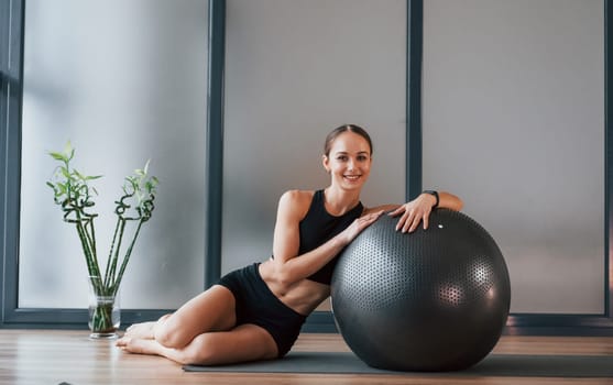 Taking a break. Young woman in sportive wear and with slim body have fitness yoga day indoors.