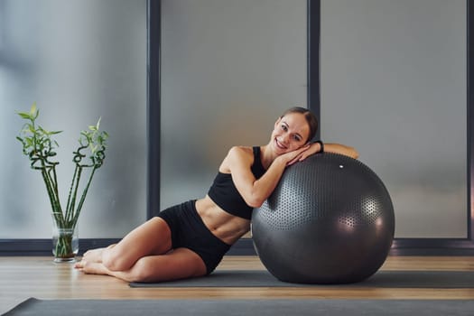 Taking a break. Young woman in sportive wear and with slim body have fitness yoga day indoors.