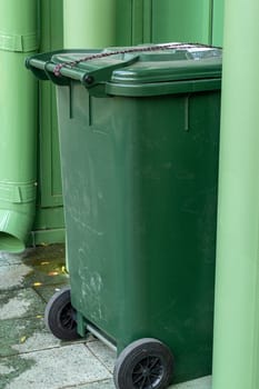 Plastic green trash can on the street for collecting food waste. Garbage collection. Conscious consumption. Concern for the environment.