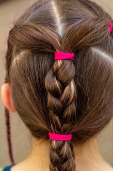 The head of the girl's child is rear view, the hair is braided. Hairstyle for children. Hairdressing. Taking care of yourself.