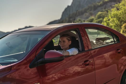 Woman driving a car. A lady in sunglasses takes the wheel of her new car. Rides along the road against the backdrop of mountains and the sea