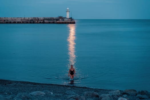 Woman The full moon rises to the lighthouse, the lunar path along the sea leads to the woman