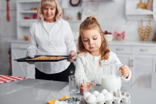 Finished product. Senior grandmother with her little granddaughter cooks sweets for Christmas on the kitchen.