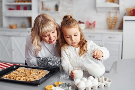 Finished product. Senior grandmother with her little granddaughter cooks sweets for Christmas on the kitchen.