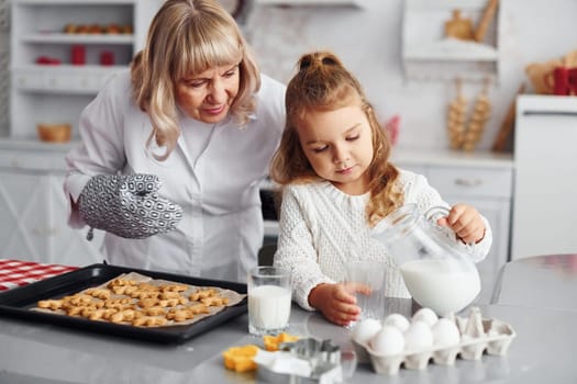 Finished product. Senior grandmother with her little granddaughter cooks sweets for Christmas on the kitchen.