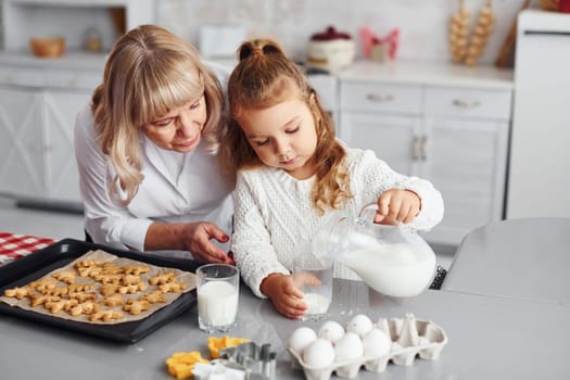 Finished product. Senior grandmother with her little granddaughter cooks sweets for Christmas on the kitchen.