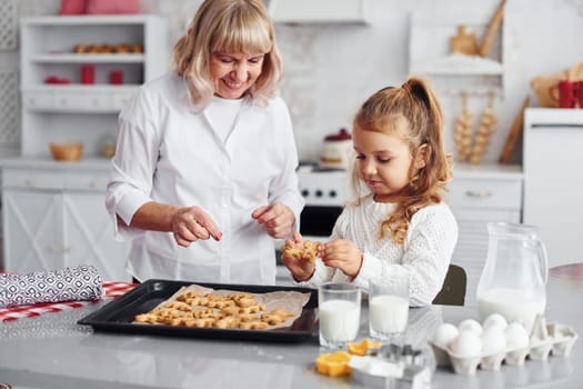 Finished product. Senior grandmother with her little granddaughter cooks sweets for Christmas on the kitchen.