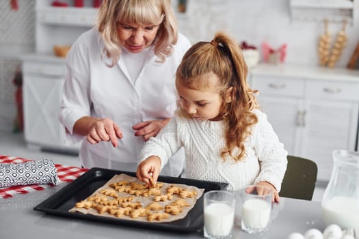Finished product. Senior grandmother with her little granddaughter cooks sweets for Christmas on the kitchen.