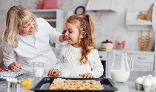 Finished product. Senior grandmother with her little granddaughter cooks sweets for Christmas on the kitchen.