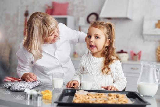 Ready to eat. Senior grandmother with her little granddaughter cooks sweets for Christmas on the kitchen.