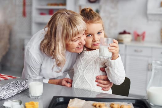 Ready to eat. Senior grandmother with her little granddaughter cooks sweets for Christmas on the kitchen.