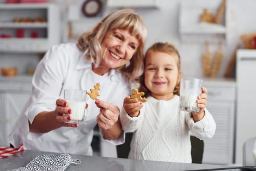 Ready to eat. Senior grandmother with her little granddaughter cooks sweets for Christmas on the kitchen.