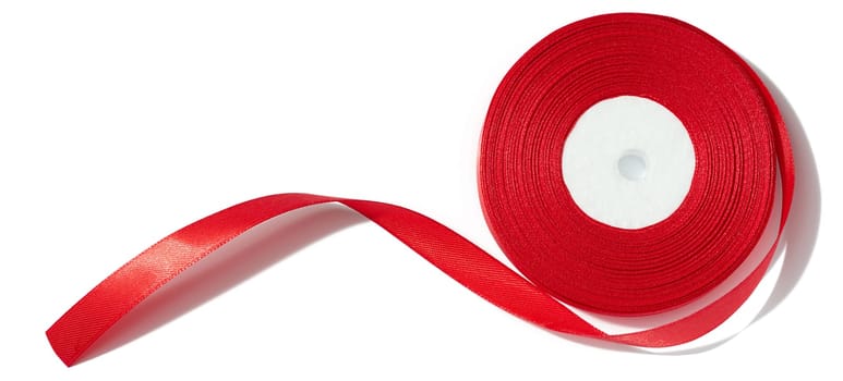 A spool with a red silk ribbon on a white isolated background, an object for decoration