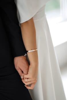 groom in a black suit with a bow tie and the bride in a tight white dress in a bright studio