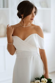 brunette bride in a tight wedding dress in a bright studio with a bouquet