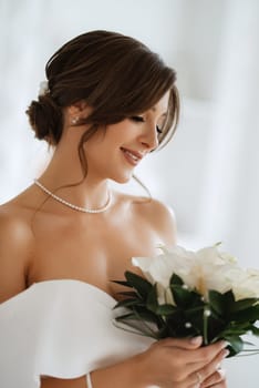 brunette bride in a tight wedding dress in a bright studio with a bouquet