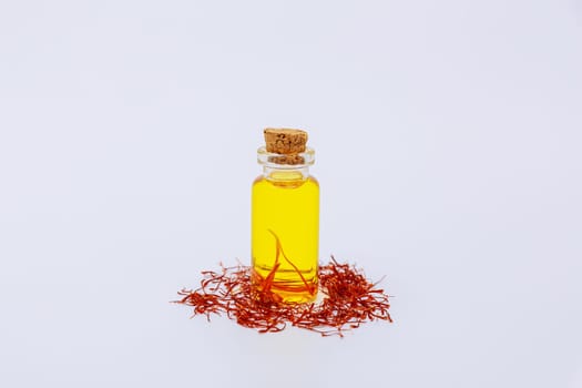 Oil extract from saffron stamens on a white background. Dry threads of saffron.