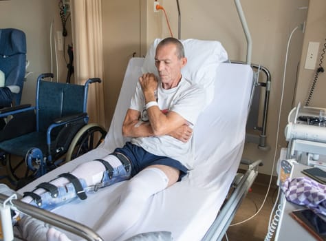 a man with a broken leg in an orthese in bed in a clinic after an accident, High quality photo