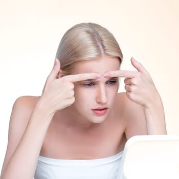 Acne problem troubling personable worried woman with natural beauty skin checking her face squeezing pimple spots in isolated background. Copyspace for blemish skincare treatment problem.