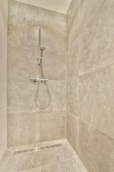 a shower in a bathroom with marble tiles on the walls and flooring around the shower head, which is attached to the wall