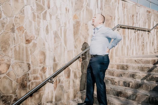Portrait of a senior professional man in a suit with various problems. A middle-aged businessman with a briefcase descends the stairs.