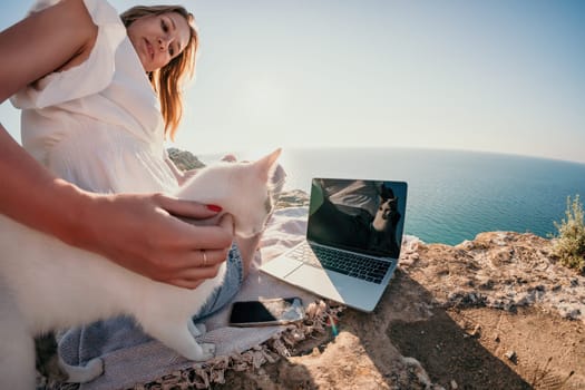 Woman sea laptop. Business woman in yellow hat working on laptop by sea. Close up on hands of pretty lady typing on computer outdoors summer day. Freelance, digital nomad, travel and holidays concept.