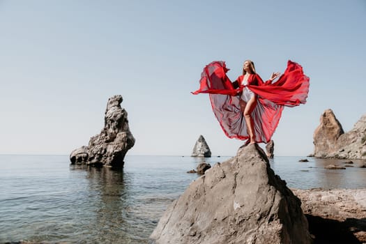 Woman travel sea. Happy tourist taking picture outdoors for memories. Woman traveler looks at the edge of the cliff on the sea bay of mountains, sharing travel adventure journey.