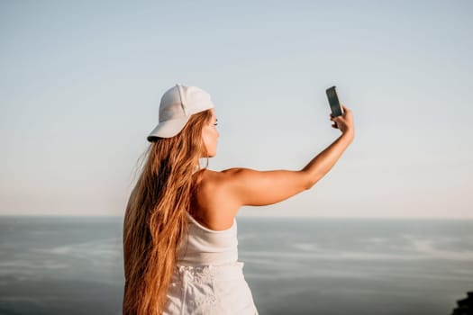 Woman travel sea. Young Happy woman in a long red dress posing on a beach near the sea on background of volcanic rocks, like in Iceland, sharing travel adventure journey