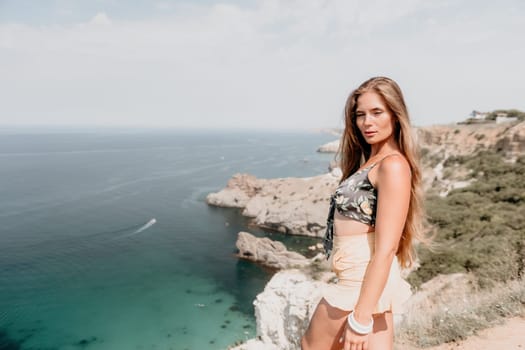 Woman travel sea. Happy tourist taking picture outdoors for memories. Woman traveler looks at the edge of the cliff on the sea bay of mountains, sharing travel adventure journey.