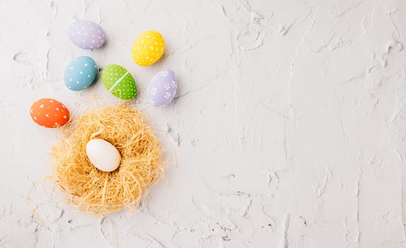 Happy Easter Day Concept. Flat lay of holiday banner background web design easter eggs in brown nest on white cement background with empty copy space, celebration greeting card, overhead, template