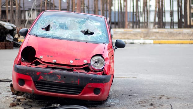 Rusty and broken red abandoned car on the city street. Abandoned old car accident outdoors. Old abandoned rusty car without wheels on the side of the road