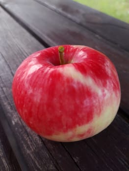 Ripe red apple on a wooden bench close-up. Beautiful ripe apple.