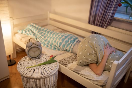 A person hides his head under a large pillow. A girl under a soft blanket.