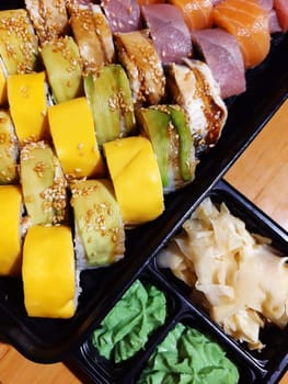 Sushi with fish and cheese, ginger and wasabi close-up on the table.