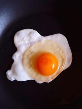 Chicken egg in a frying pan close up top view.