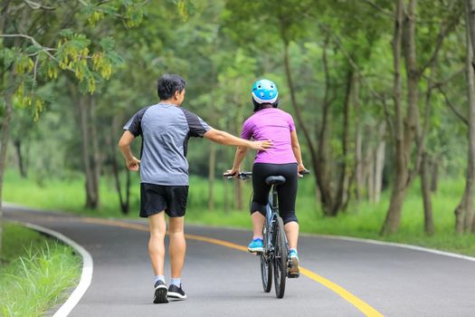 Middle aged couple walking with their bicycle in park