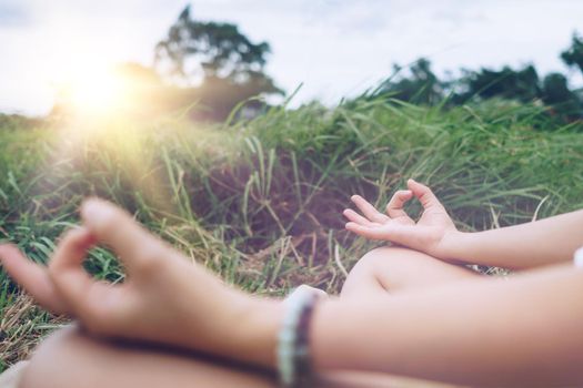 Woman practicing yoga lesson, breathing, meditating exercise, outdoor in grass field. Well being, wellness concept