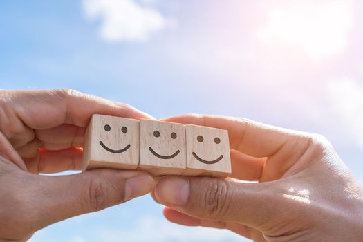 Smile face and cart icon on wood cube. Optimistic person or people feeling inside and service rating when shopping, satisfaction concept in business.