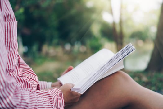 Woman is reading book in beautiful park and pond relax and peaceful environment background.