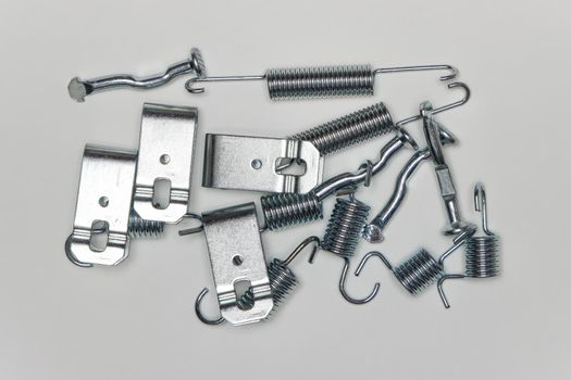 A set of metal components in a heap on the table, parts for car repair. A set of spare parts for servicing vehicle calipers. Details on white background, copy space available.