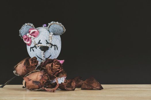 Teddy Bear with Dry roses on wooden table